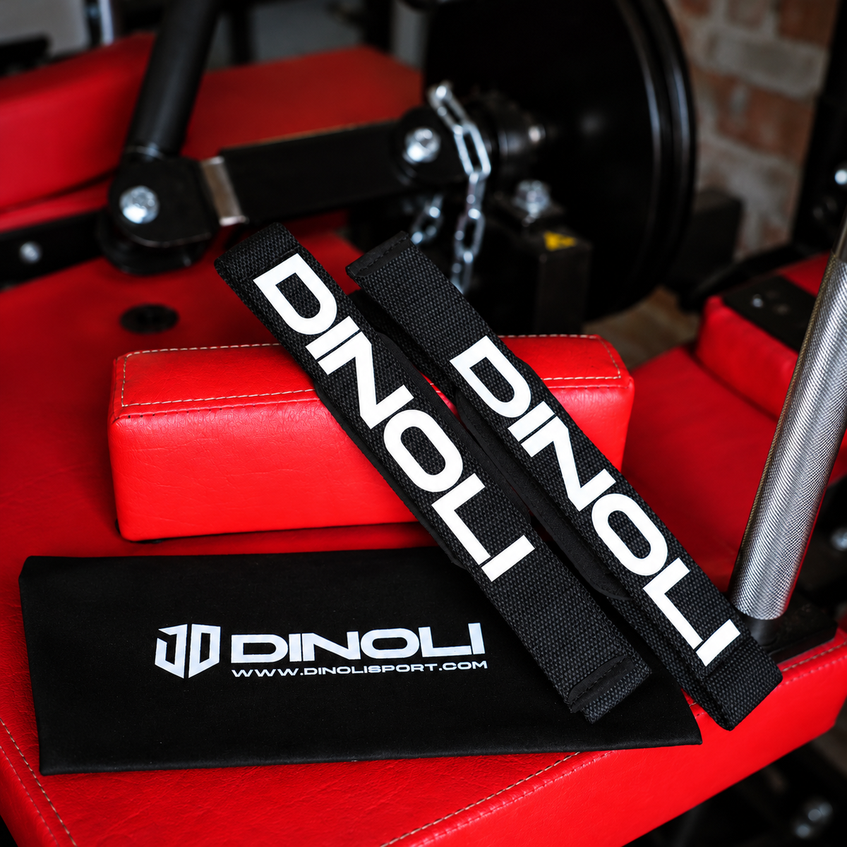DINOLI black auto-lock lifting straps with white branding and matching storage pouch displayed on a red gym bench.